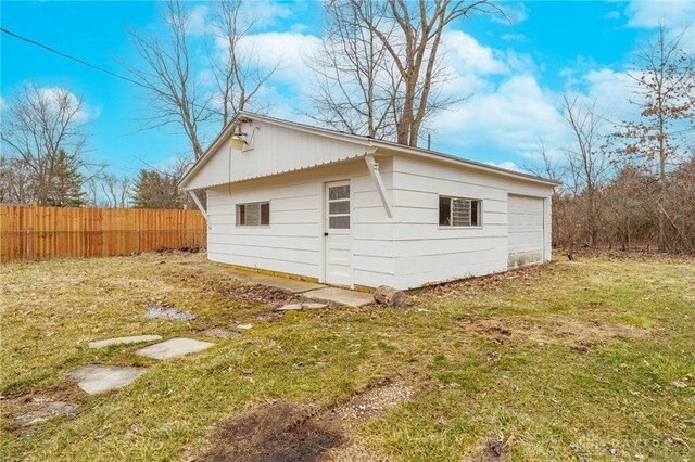 view of side of home featuring an outbuilding, a yard, and fence