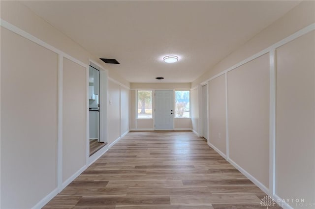 hallway with light wood-style flooring and a decorative wall