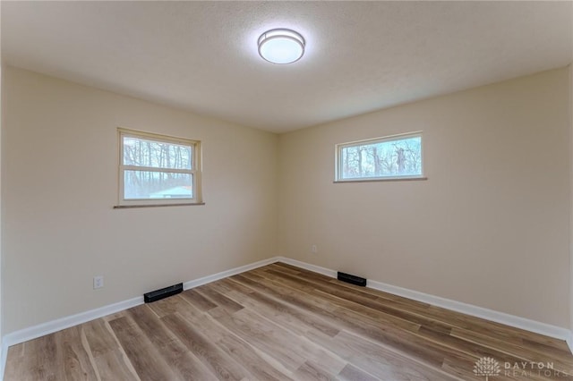 empty room with visible vents, baseboards, and wood finished floors