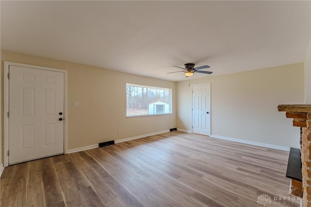 unfurnished living room featuring wood finished floors, visible vents, baseboards, a fireplace, and ceiling fan