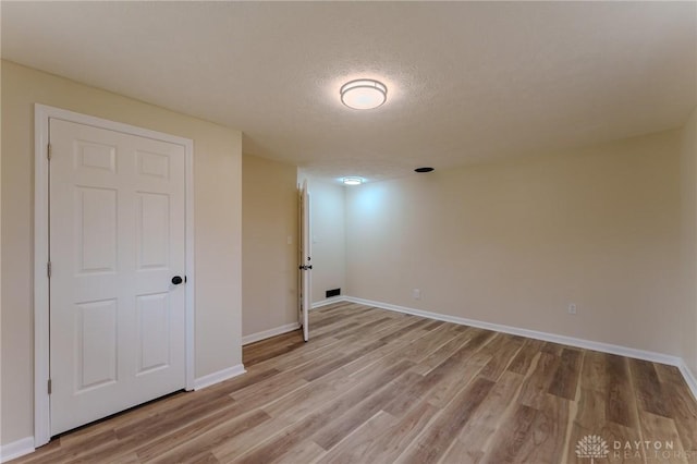 interior space with light wood finished floors, a textured ceiling, and baseboards