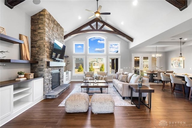 living room featuring dark wood-style floors, a stone fireplace, ceiling fan with notable chandelier, and high vaulted ceiling