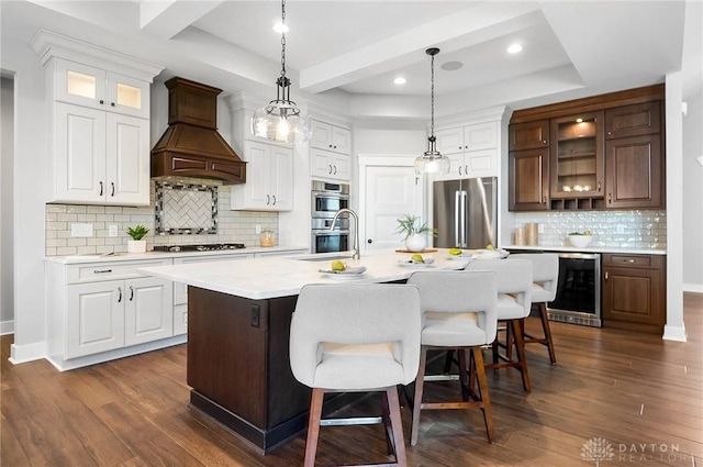 kitchen with premium range hood, wine cooler, light countertops, a tray ceiling, and appliances with stainless steel finishes