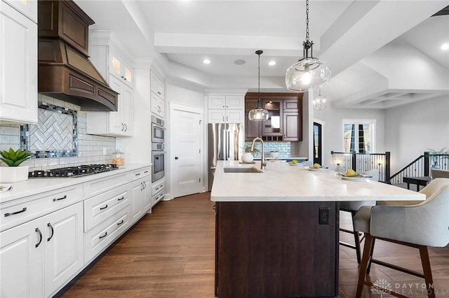 kitchen featuring a sink, light countertops, dark wood-style floors, stainless steel appliances, and a kitchen island with sink