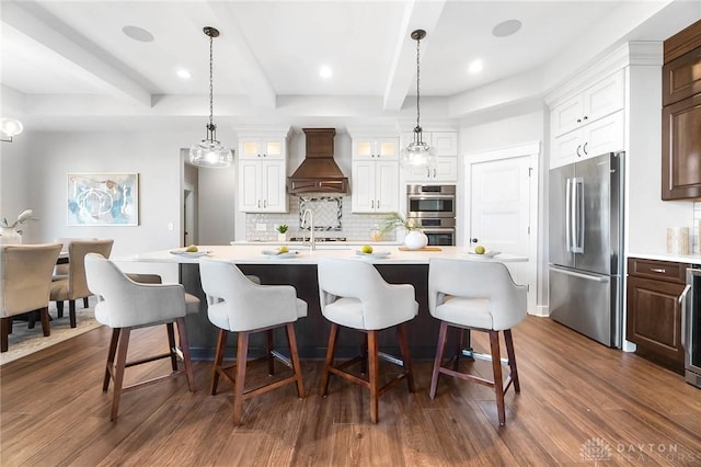 kitchen with premium range hood, beamed ceiling, dark wood finished floors, stainless steel appliances, and light countertops