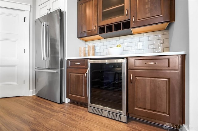 kitchen featuring wood finished floors, beverage cooler, freestanding refrigerator, light countertops, and tasteful backsplash