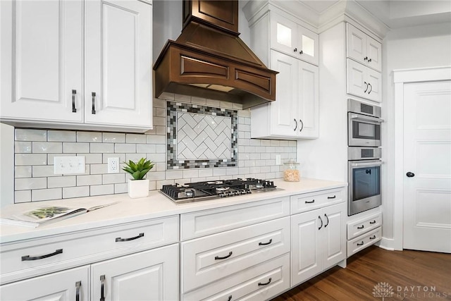 kitchen with dark wood-type flooring, appliances with stainless steel finishes, white cabinets, light countertops, and custom exhaust hood