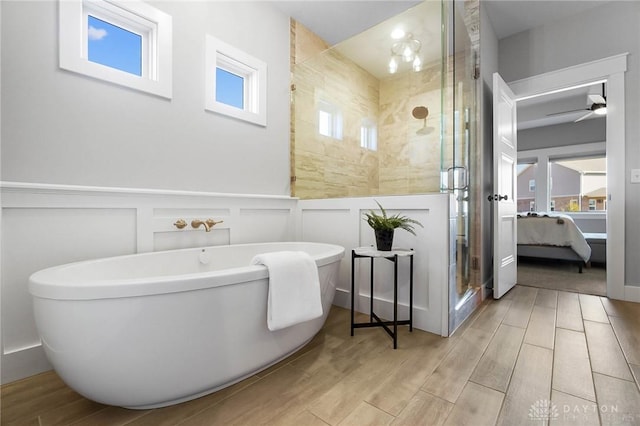 ensuite bathroom with wood tiled floor, a wainscoted wall, a stall shower, ensuite bathroom, and a soaking tub