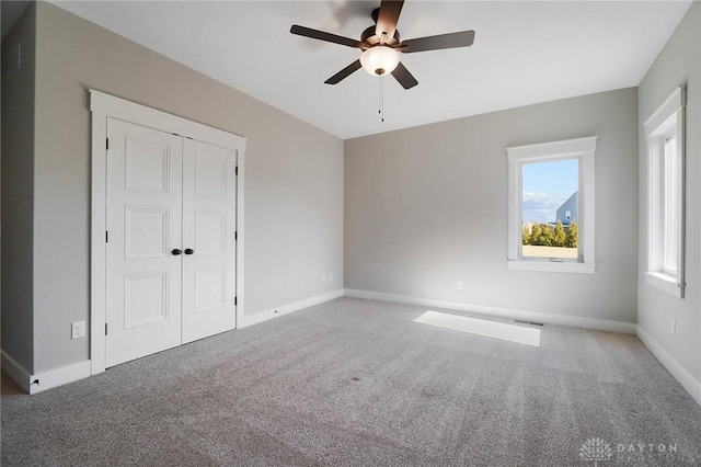 unfurnished bedroom featuring a closet, carpet flooring, a ceiling fan, and baseboards