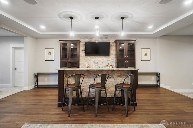 bar featuring wet bar, a tray ceiling, and dark wood-style flooring