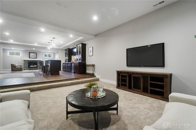 carpeted living area featuring a tray ceiling, visible vents, and recessed lighting