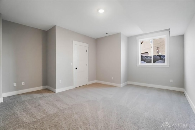 spare room with baseboards and light carpet