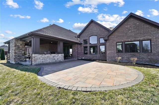 rear view of property with a patio, a yard, and brick siding