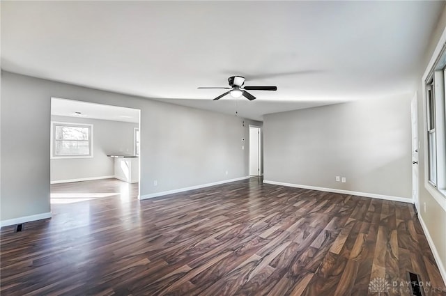 empty room featuring baseboards, dark wood-type flooring, and ceiling fan