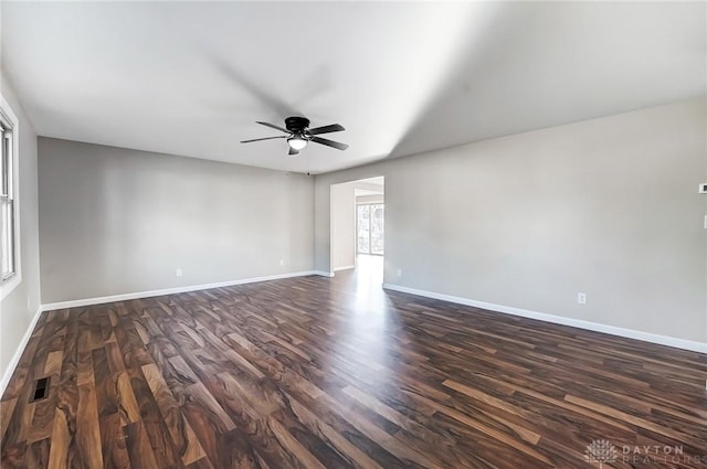 empty room with a ceiling fan, visible vents, dark wood-style flooring, and baseboards