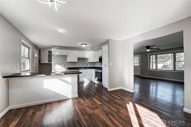 kitchen with white cabinetry, dark countertops, a peninsula, and a wealth of natural light