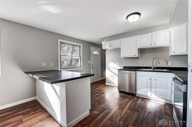 kitchen with a sink, dark countertops, white cabinetry, stainless steel appliances, and a peninsula