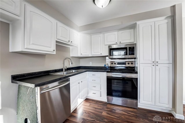 kitchen featuring a sink, dark countertops, appliances with stainless steel finishes, and white cabinets