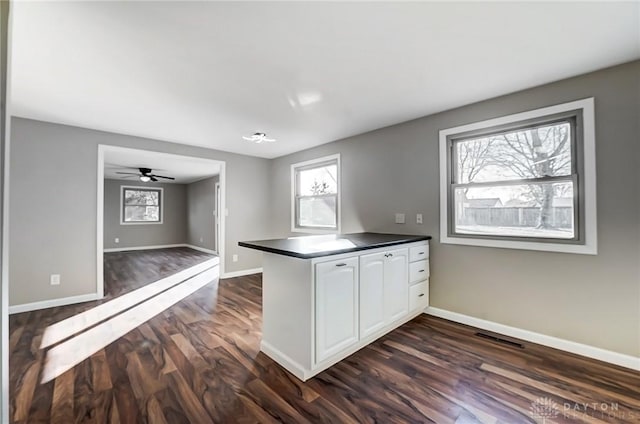 kitchen with plenty of natural light, dark countertops, a peninsula, and dark wood-style flooring