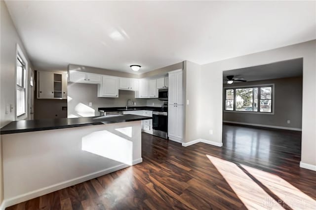 kitchen featuring dark countertops, appliances with stainless steel finishes, white cabinets, a ceiling fan, and a sink