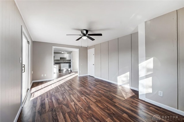 unfurnished living room with dark wood finished floors, a sink, baseboards, and ceiling fan