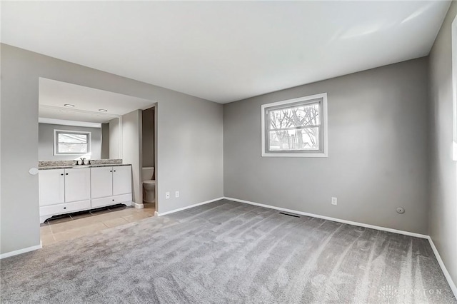 interior space featuring baseboards, plenty of natural light, and light colored carpet