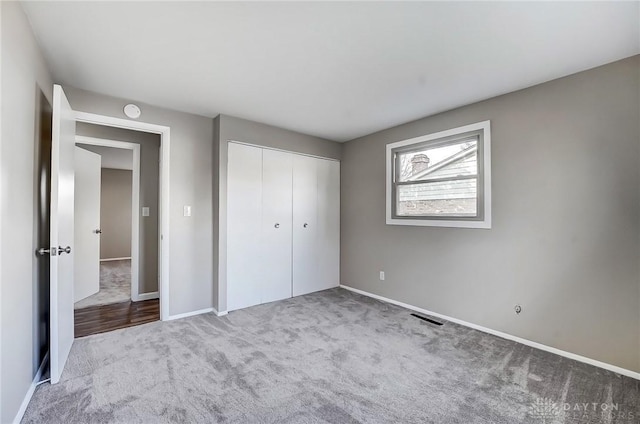 unfurnished bedroom featuring a closet, visible vents, baseboards, and carpet floors