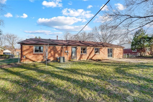 back of property with brick siding, central air condition unit, a lawn, and fence