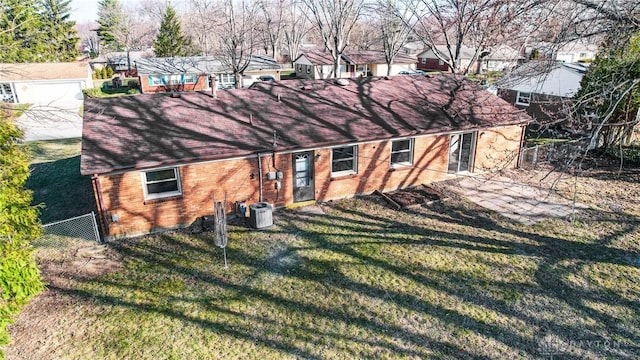 view of front of home featuring brick siding, fence, central air condition unit, a residential view, and a front yard