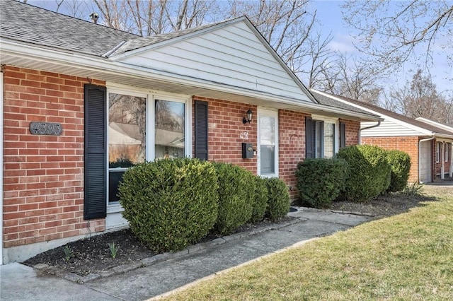 view of front of house featuring brick siding and roof with shingles