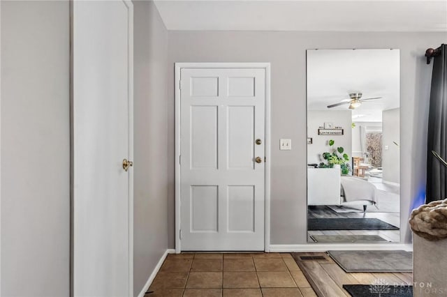 foyer featuring tile patterned floors, a ceiling fan, and baseboards