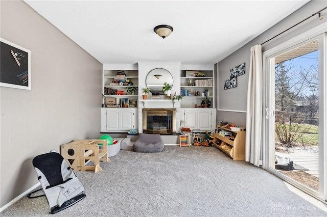 interior space featuring a glass covered fireplace, built in shelves, and carpet