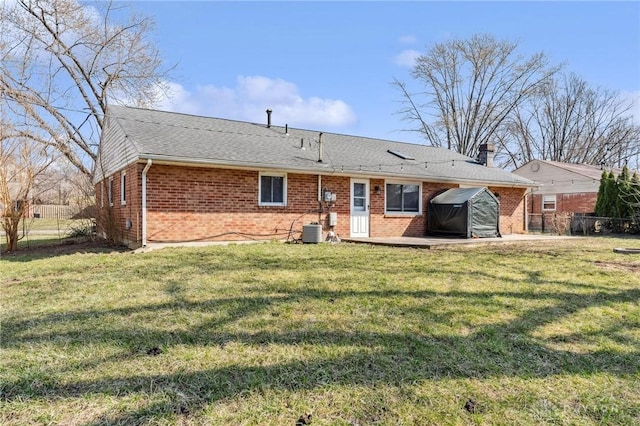 back of property with brick siding, fence, central AC unit, a yard, and a patio area