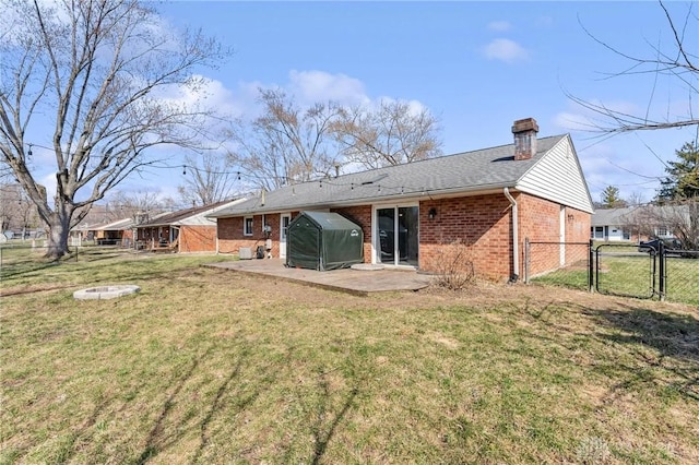 rear view of house featuring brick siding, fence, a yard, a patio, and a gate