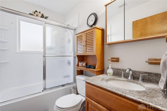 bathroom featuring visible vents, enclosed tub / shower combo, toilet, and vanity