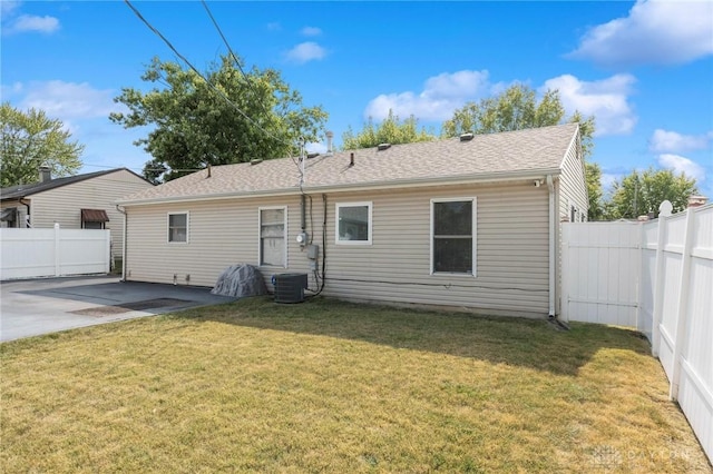 rear view of property with a yard, a patio area, a fenced backyard, and a shingled roof