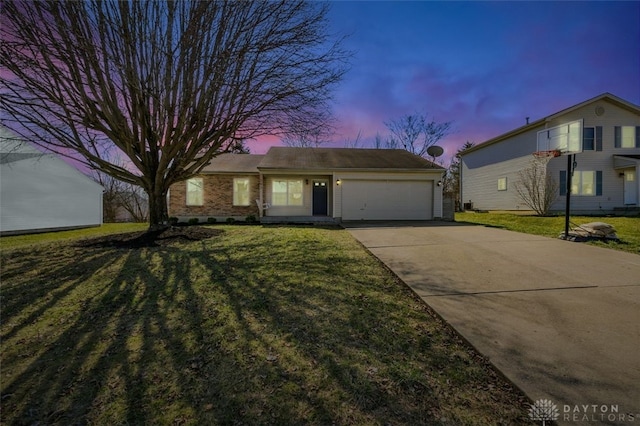 view of front of house featuring brick siding, a lawn, an attached garage, and concrete driveway