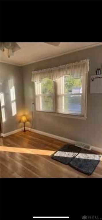 interior space with wood finished floors, a ceiling fan, and baseboards