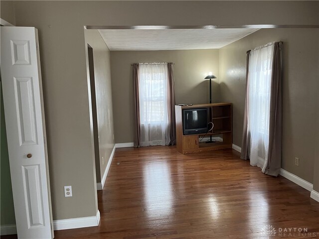 unfurnished living room featuring wood finished floors and baseboards