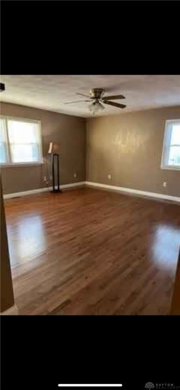 spare room featuring ceiling fan, baseboards, and wood finished floors