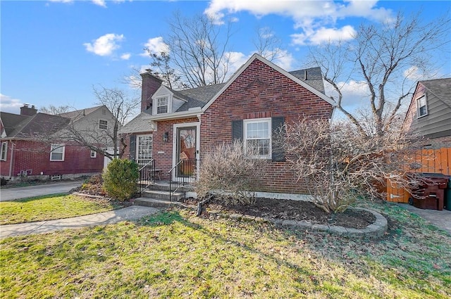 view of front of house featuring brick siding, a chimney, and fence