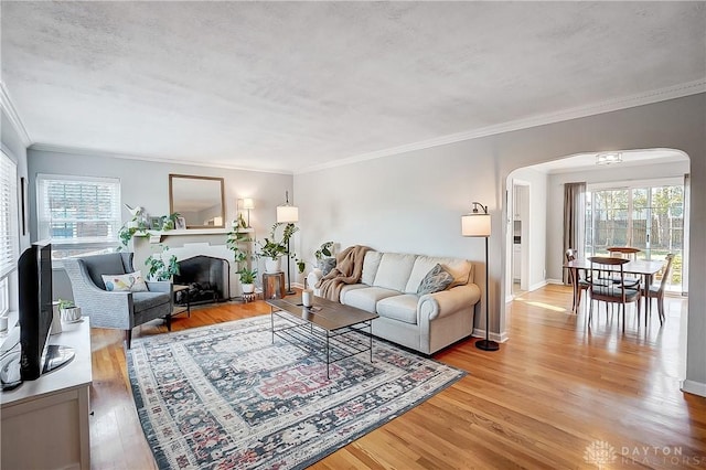 living area with arched walkways, light wood finished floors, and a wealth of natural light