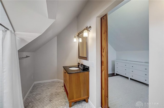 bathroom featuring baseboards, vanity, and lofted ceiling