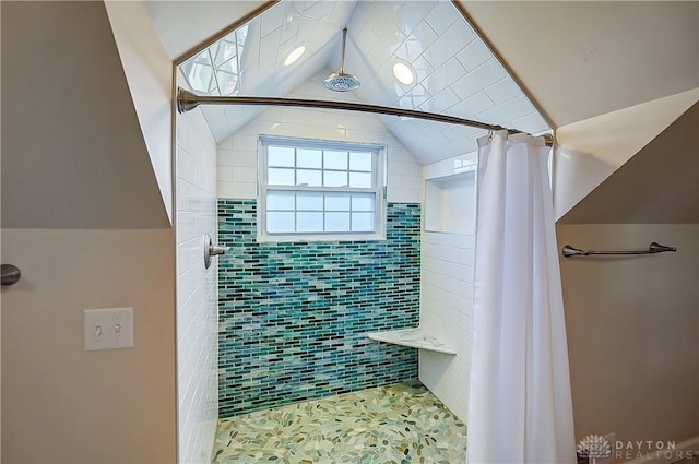 full bathroom with lofted ceiling and tiled shower