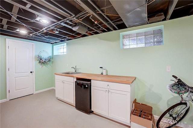 kitchen featuring a sink, wood counters, white cabinets, baseboards, and dishwasher