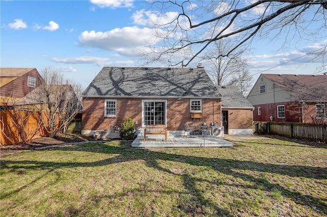 rear view of property with brick siding, a fenced backyard, and a lawn