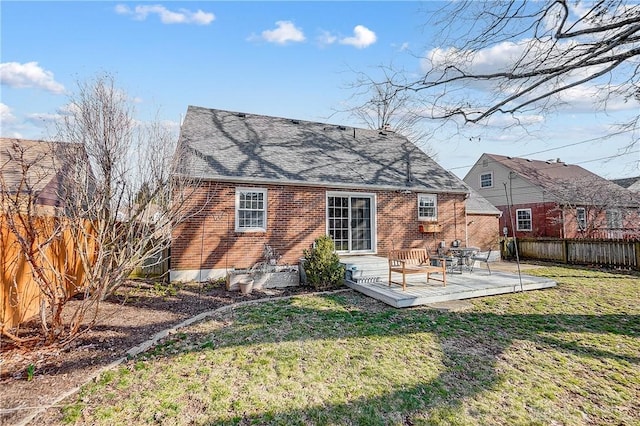 back of house with a lawn, entry steps, a fenced backyard, roof with shingles, and brick siding