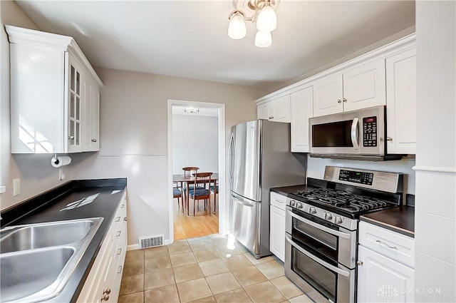 kitchen featuring visible vents, a sink, dark countertops, appliances with stainless steel finishes, and white cabinets