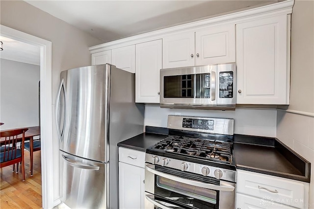 kitchen featuring light wood-style floors, stainless steel appliances, dark countertops, and white cabinetry