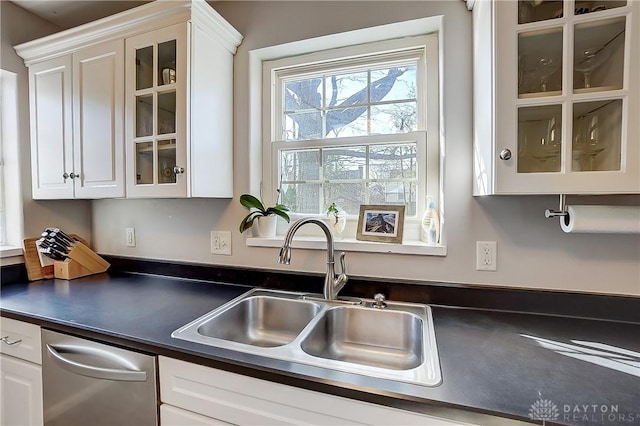 kitchen with dark countertops, white cabinets, and a sink